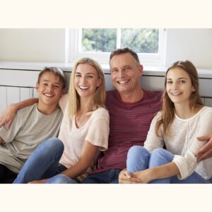 Mother and father sitting at home with their teenage son and teenage daughter, smiling together